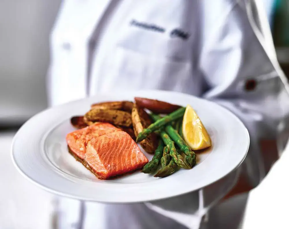 The Lodge at Wake Forest Chef Created Meals, chef delivering a finished dish.
